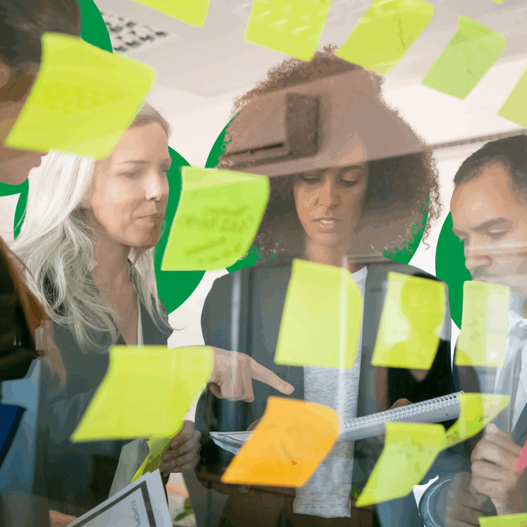 a group of people looking at sticky notes on a glass wall