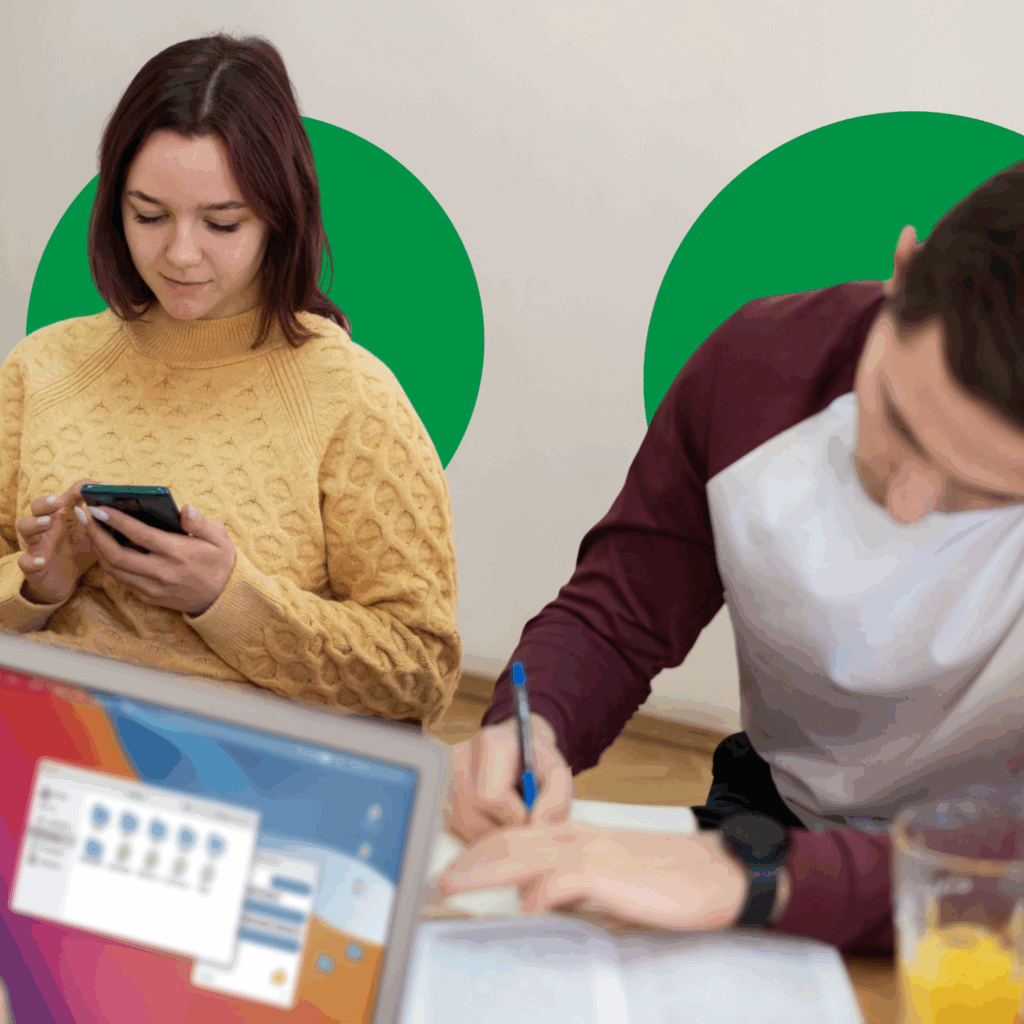 a man and woman sitting at a table with a laptop and a phone