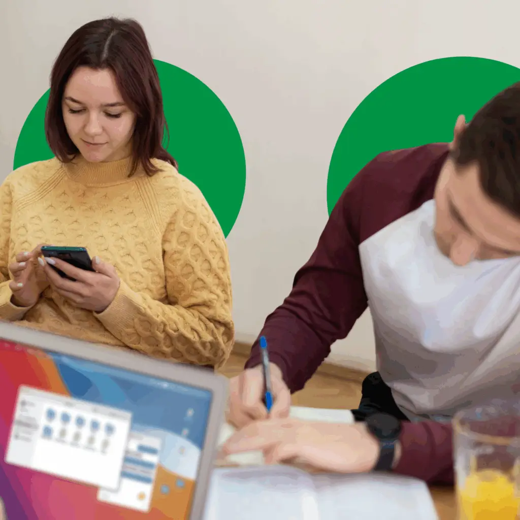a man and woman sitting at a table with a laptop and a phone